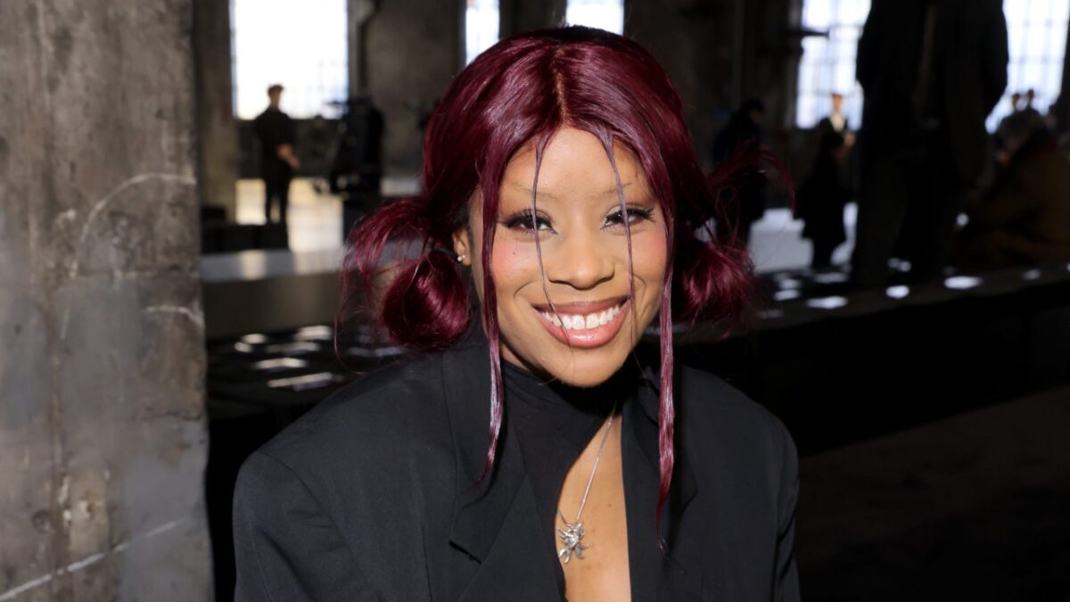 Rian Phin, a black woman with dark red space buns and face-framing strands of hair wearing a black blazer